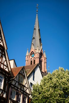 Charming view of a Gothic church tower in Calw, Germany, with traditional architecture and a bright blue sky.