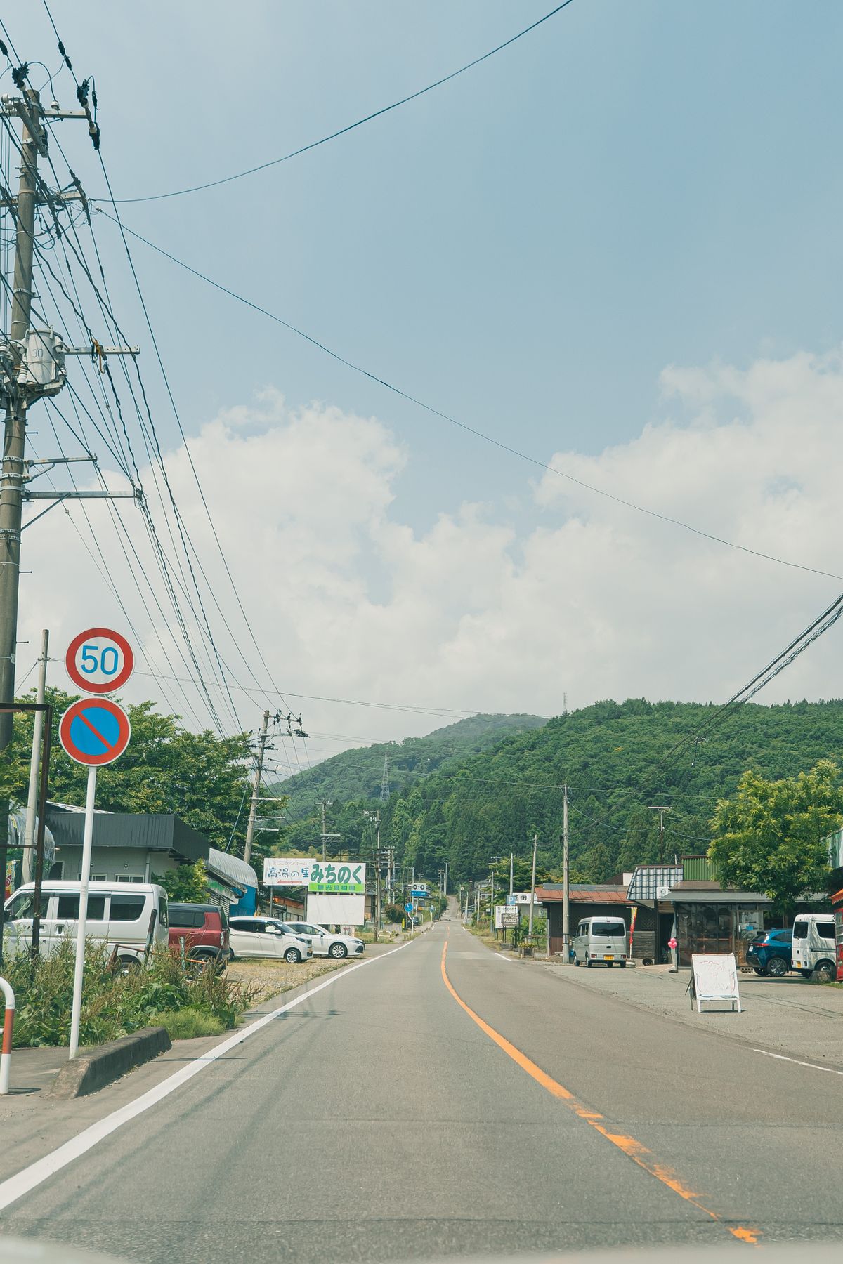 Scenic rural road through Japanese countryside with fields and mountains, similar to the inland roads of Sado