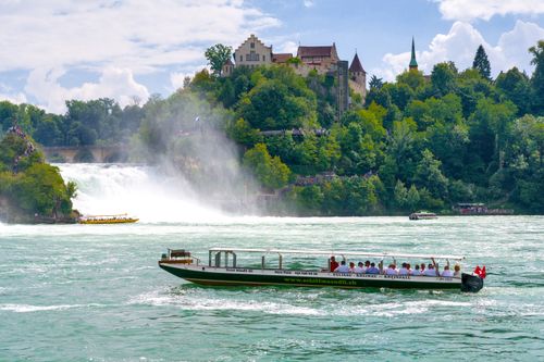 Free Tourists enjoy a boat ride near the stunning Rhine Falls in Switzerland. Stock Photo