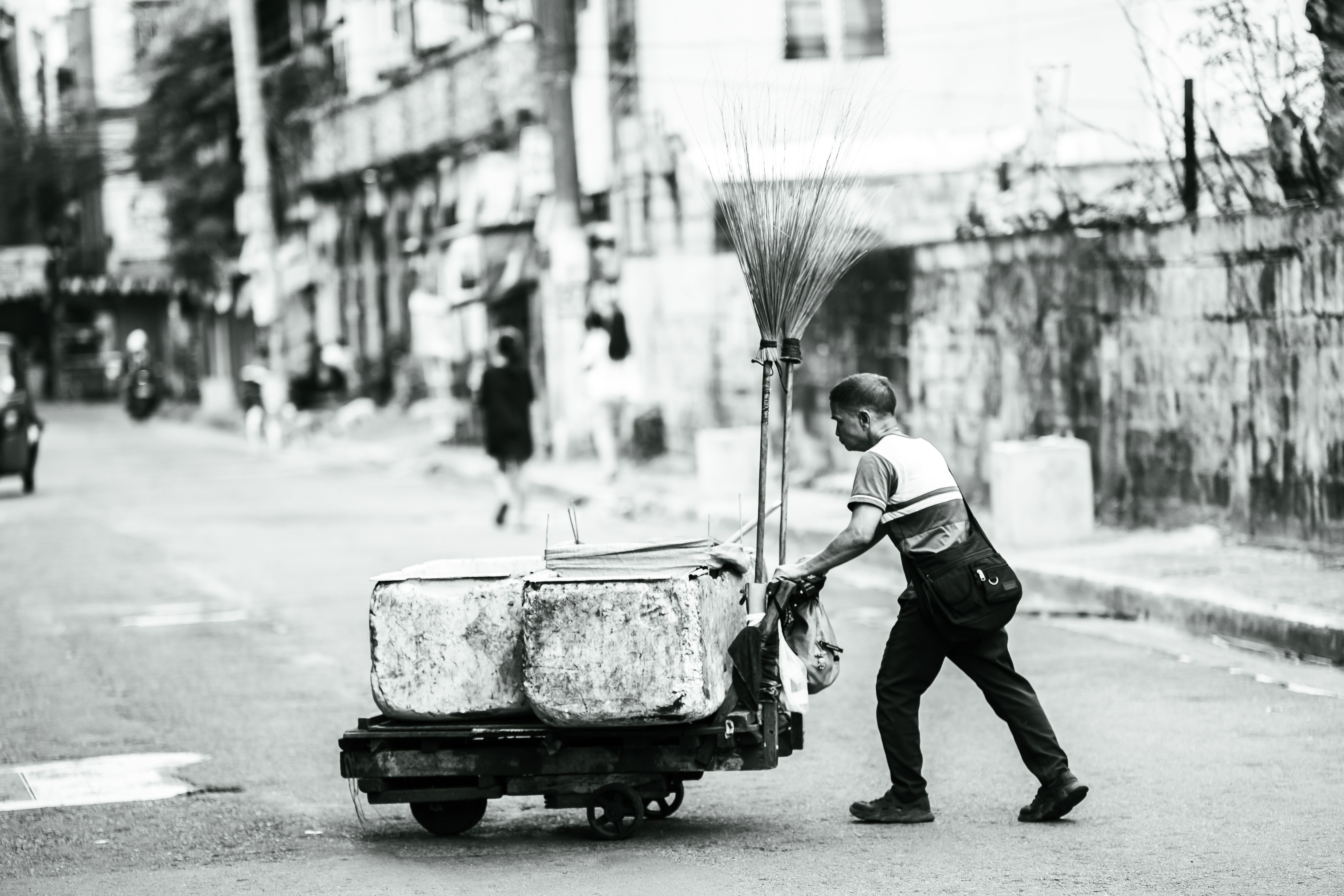 Monochrome image of a man pushing a cart on a street in Manila.