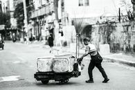 Monochrome image of a man pushing a cart on a street in Manila.
