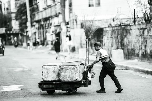 Monochrome image of a man pushing a cart on a street in Manila.