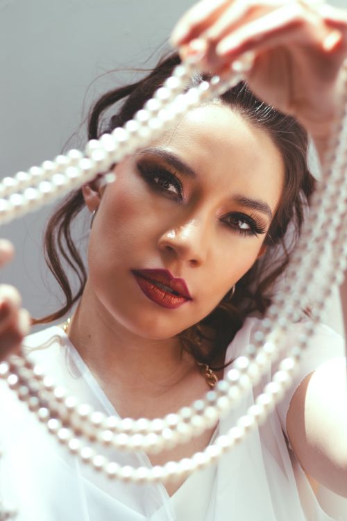 Free A close-up portrait of a woman holding a string of pearls, exuding elegance and sophistication. Stock Photo
