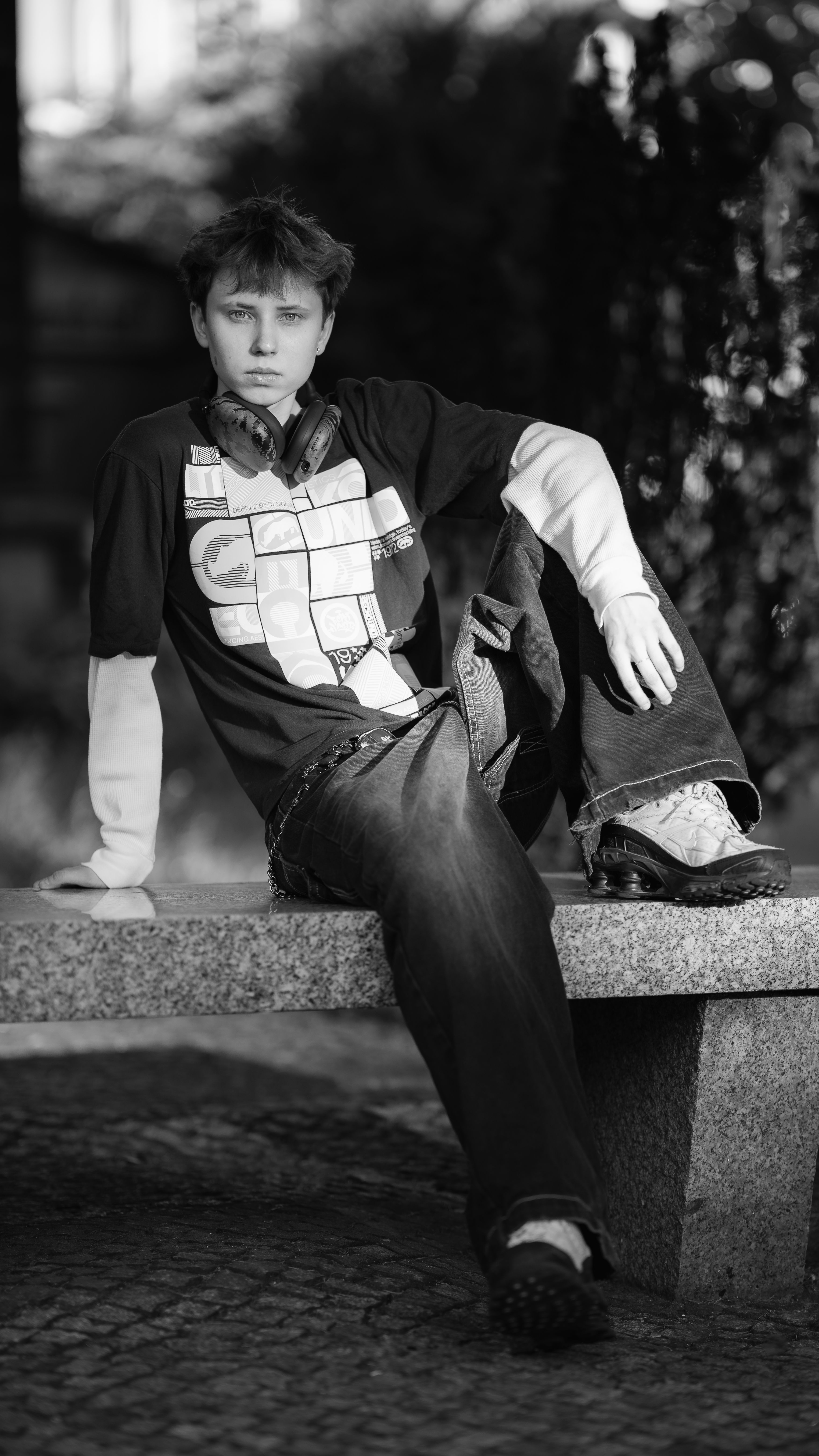Stylish young man sitting on a bench, captured in black and white.