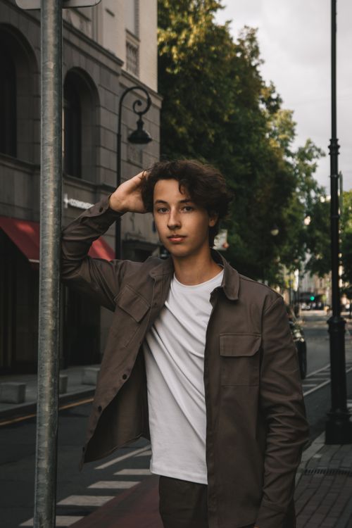 Free A young man poses confidently on a city street, exuding a relaxed urban vibe. Stock Photo
