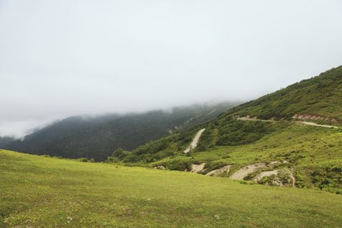 Free A serene mountain landscape with lush green hills and misty clouds. Stock Photo