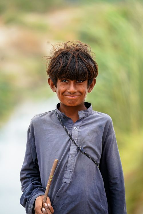 Free A joyful young boy with a charming smile stands outdoors, embodying the spirit of village life. Stock Photo