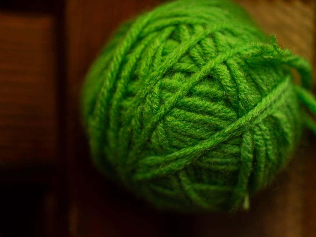 a tangled ball of neon yarn on a dark floor