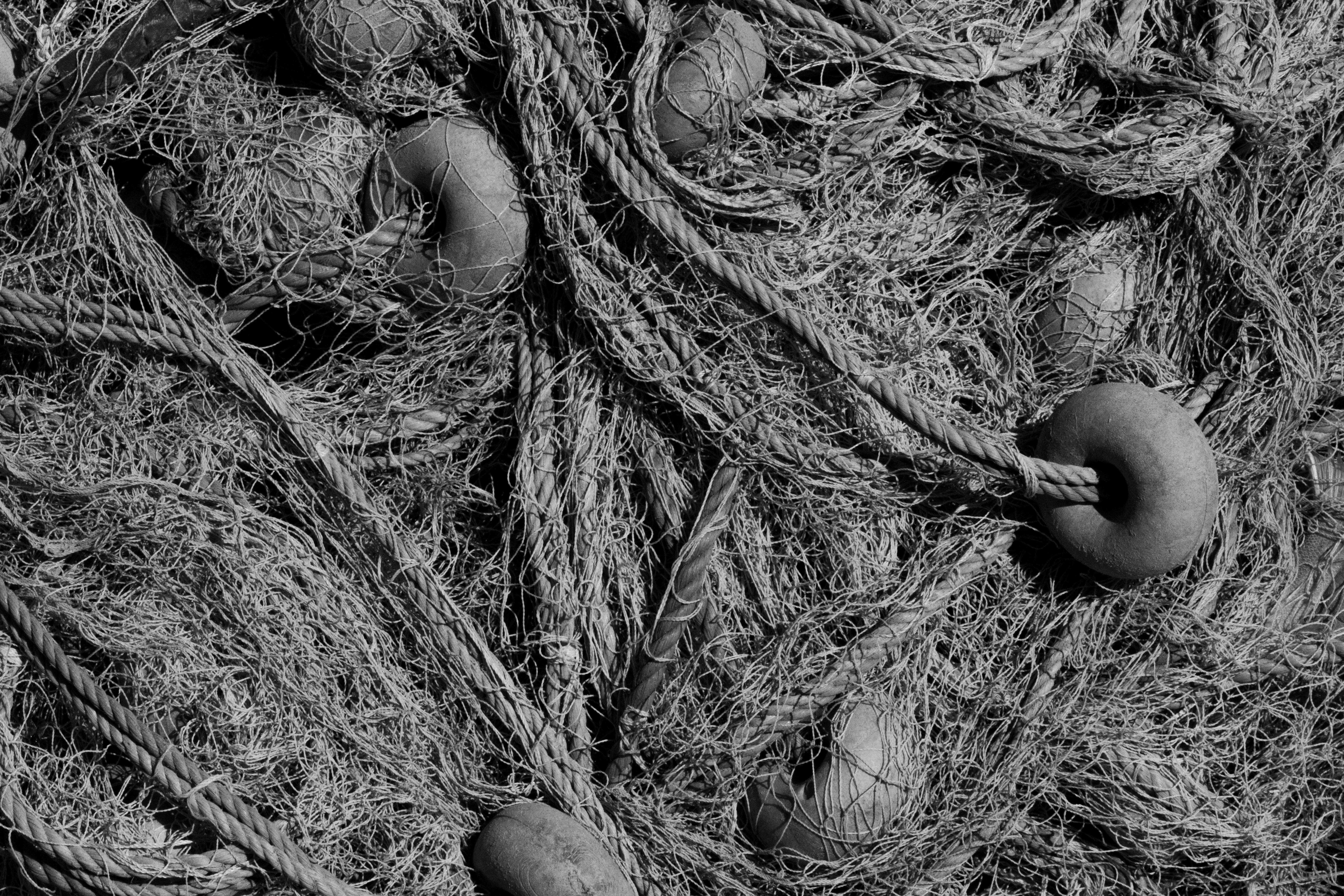 A closeup view of traditional fishing nets showcasing ropes and floats in monochrome.
