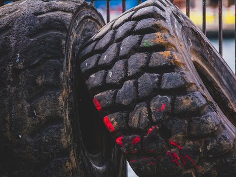 Gedetailleerde weergave van oude, versleten vrachtwagenbanden met zichtbare rode verfstrepen in een industriële buitenomgeving.