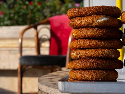 Free A close-up view of freshly baked simit stacked on a tray in an outdoor café in Antalya, Türkiye. Stock Photo