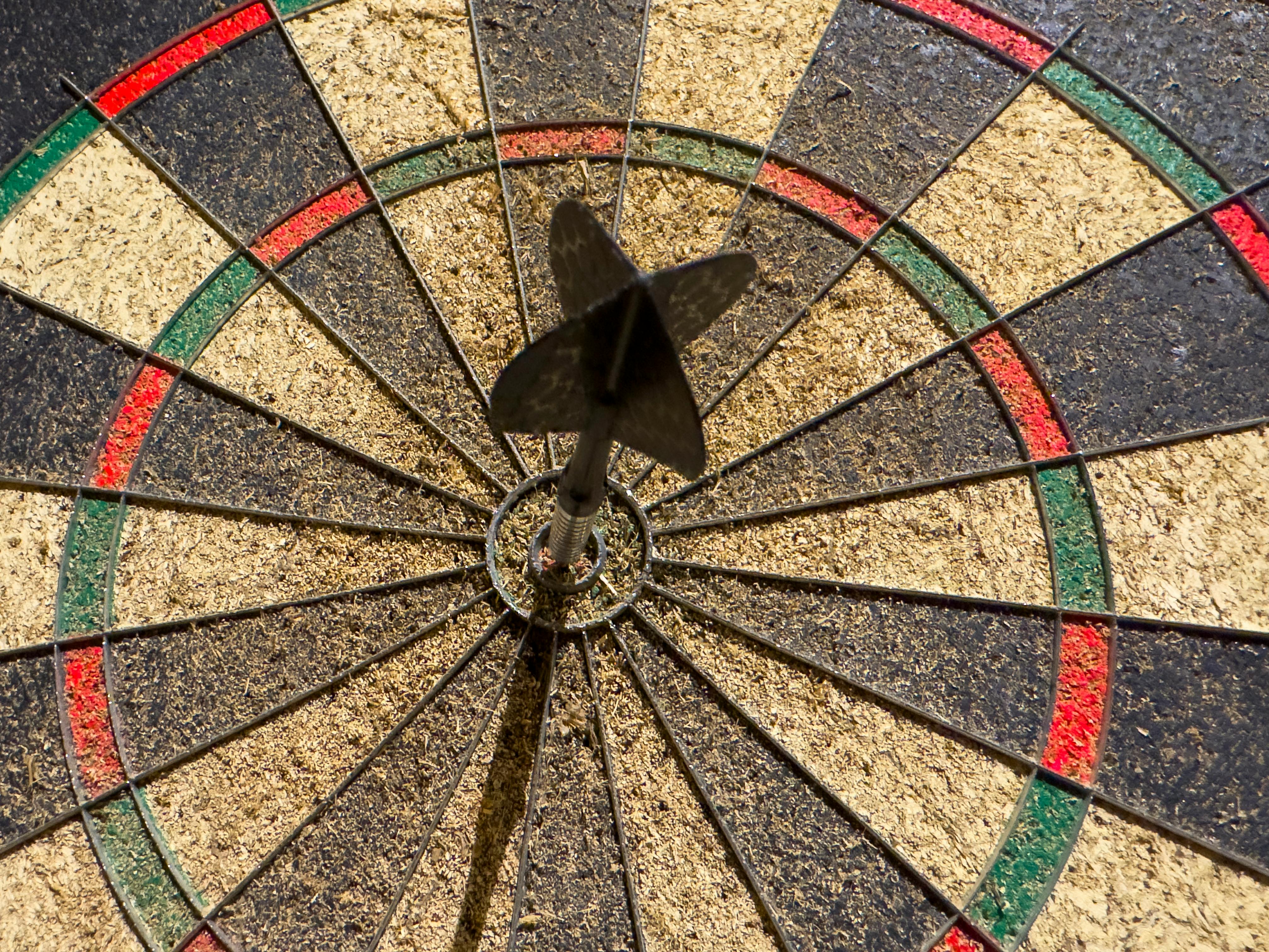 Dart perfectly hitting the bullseye on a dartboard, showcasing precision and success.