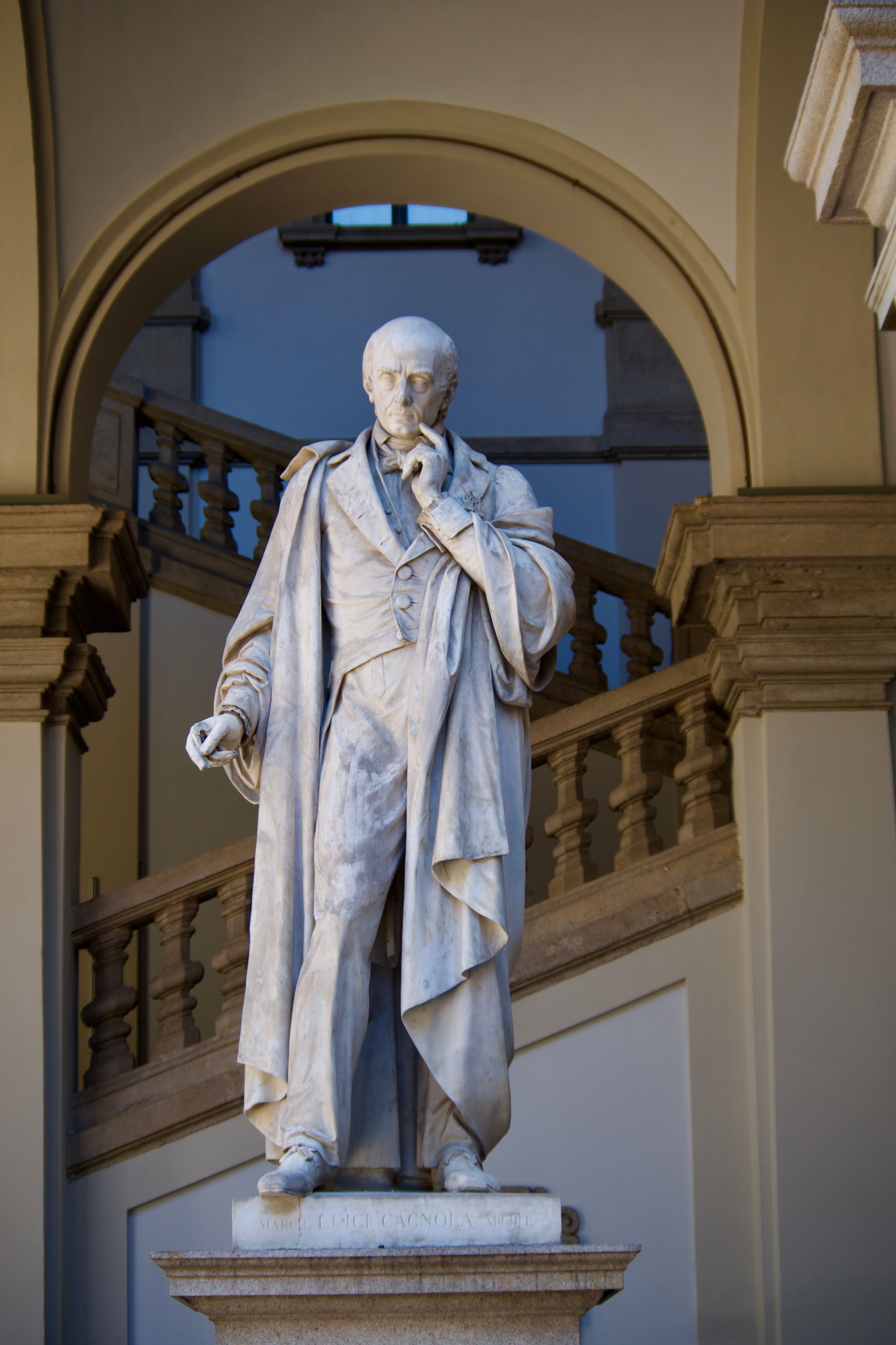 Elegant marble statue set in a classic architectural space with arches.