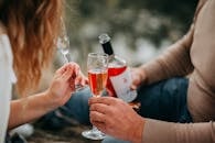 Two Persons Holding Glass Flutes While Drinking