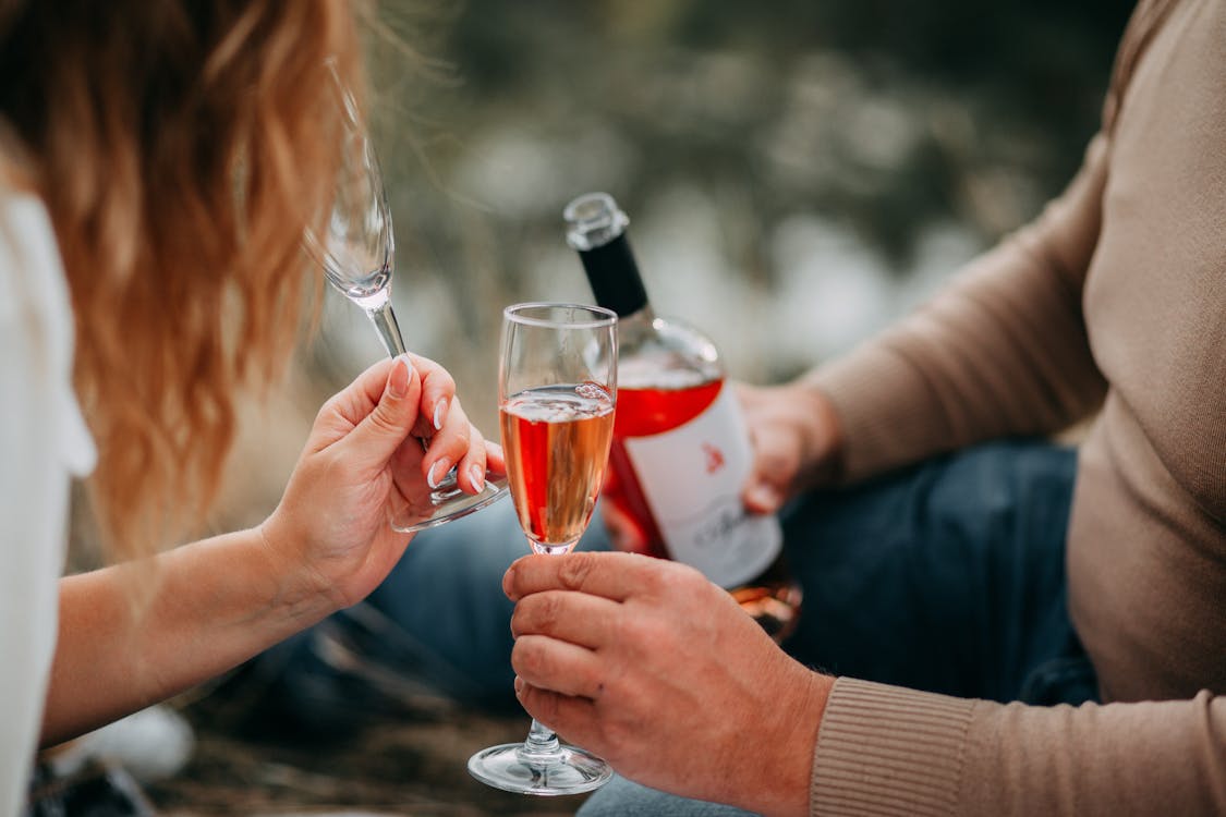 Two Persons Holding Glass Flutes While Drinking