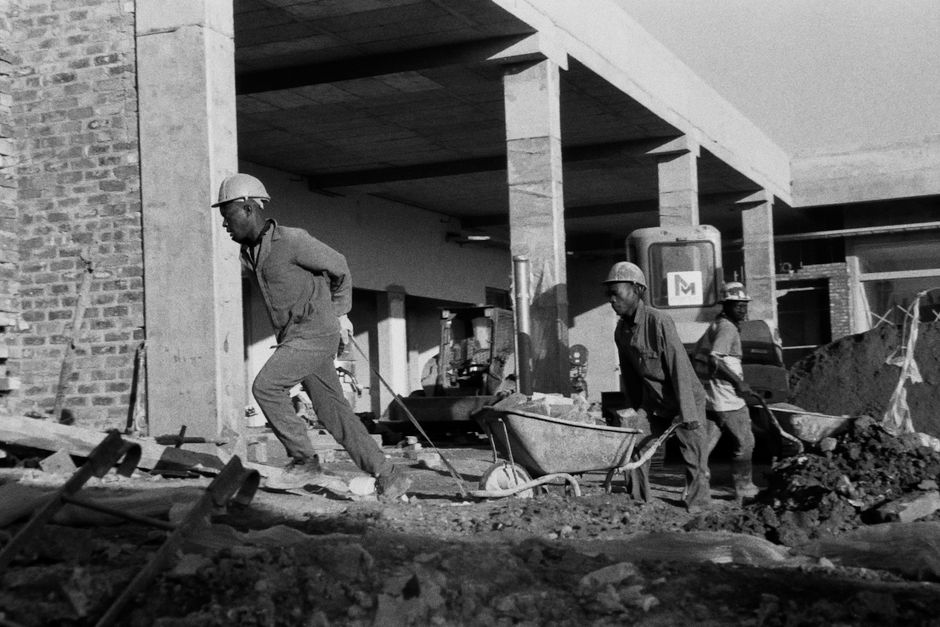 Black and white image of construction workers building a structure in Johannesburg, South Africa.