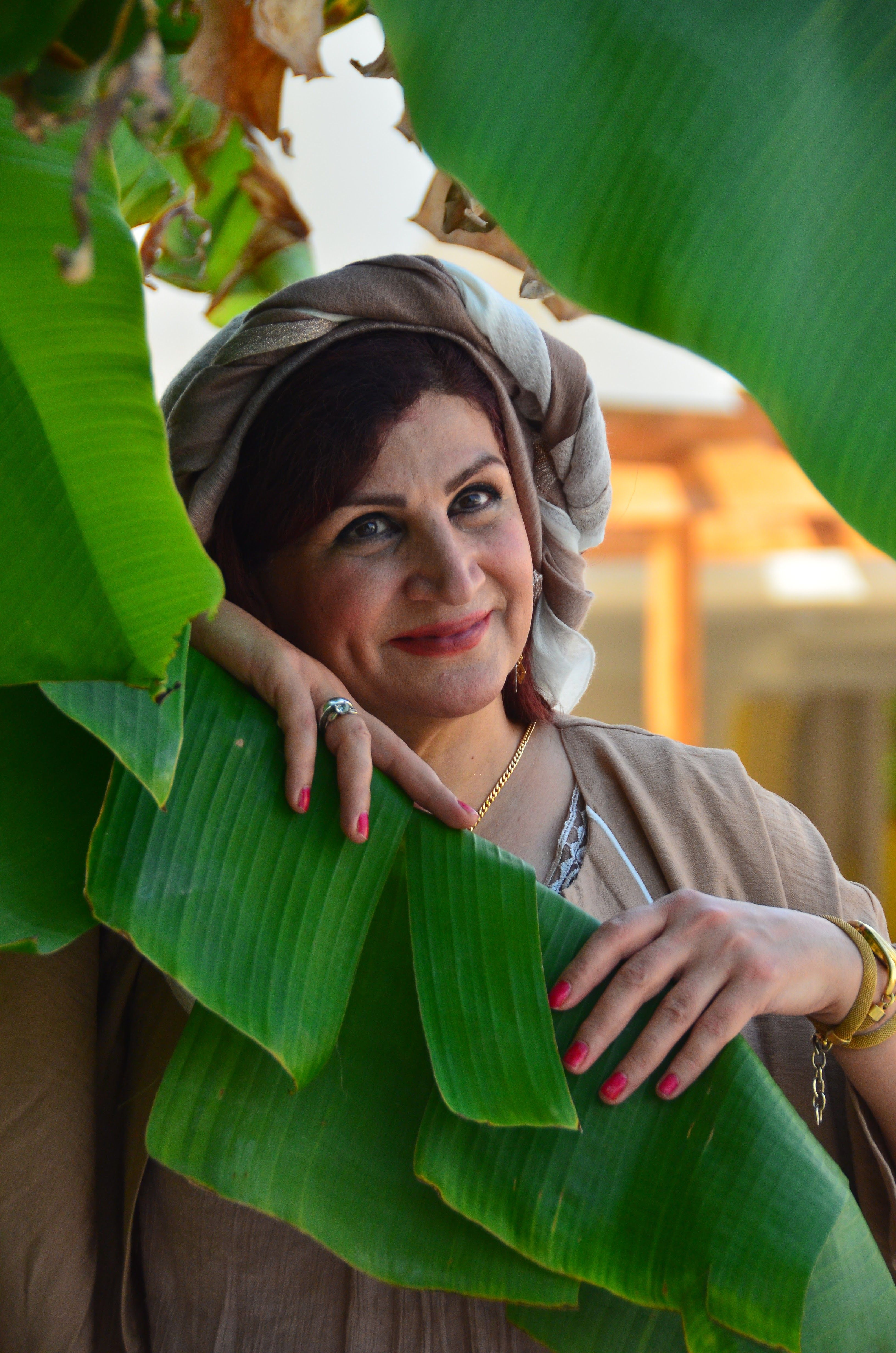Smiling Woman Posing with Green Leaves Outdoors