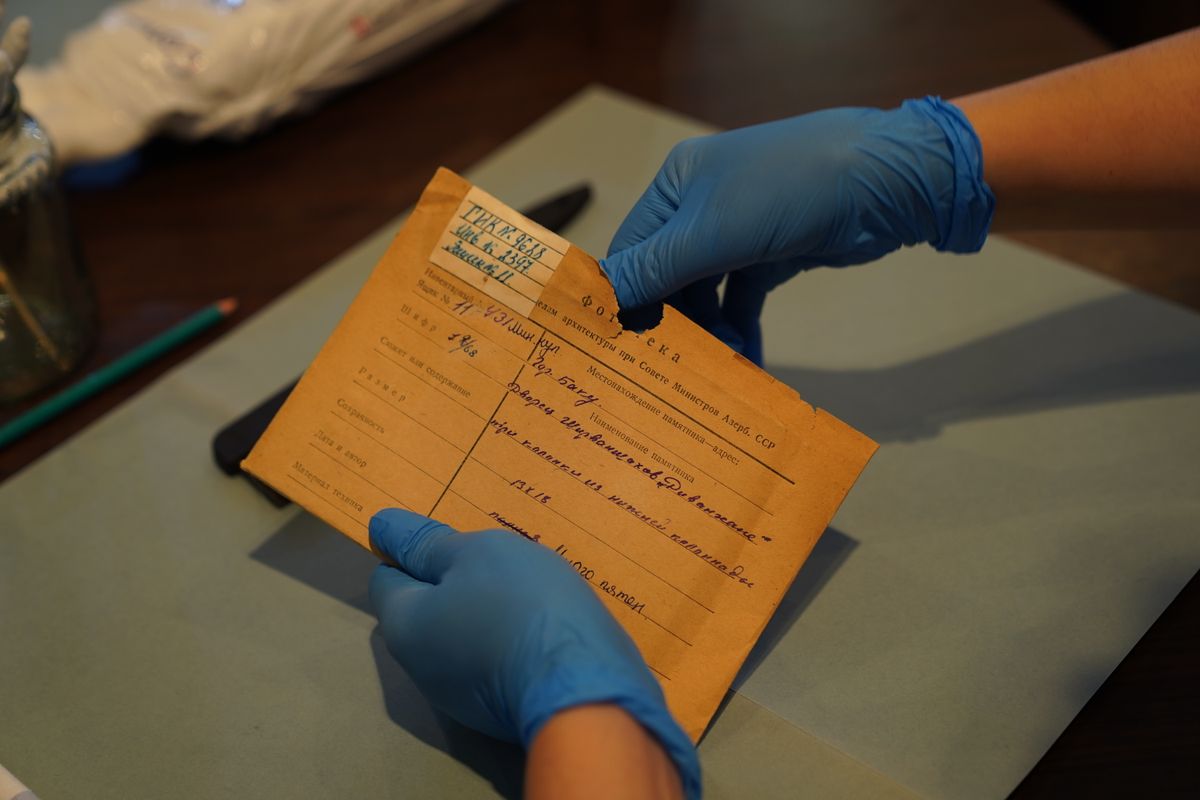 Gloved hands examining a folded archival document