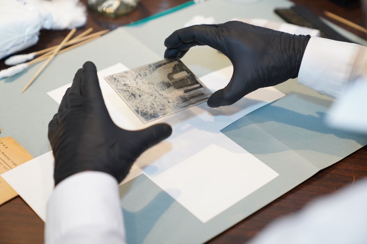 Conservator in gloves working on a paper item at a bench