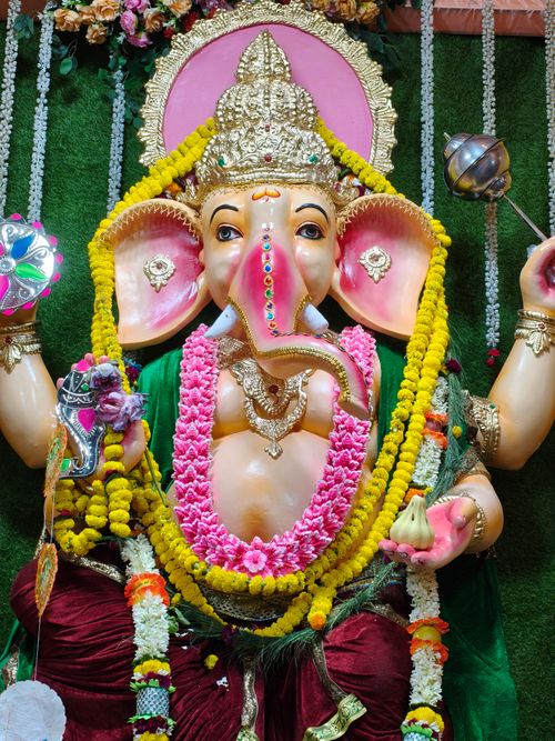 Free Colorful Ganesha idol adorned with flowers and ornaments in a traditional Indian setting. Stock Photo