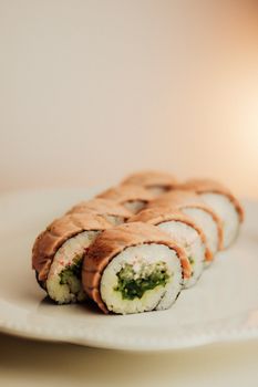 Close-up of sushi rolls with grilled salmon and green filling on a plate.