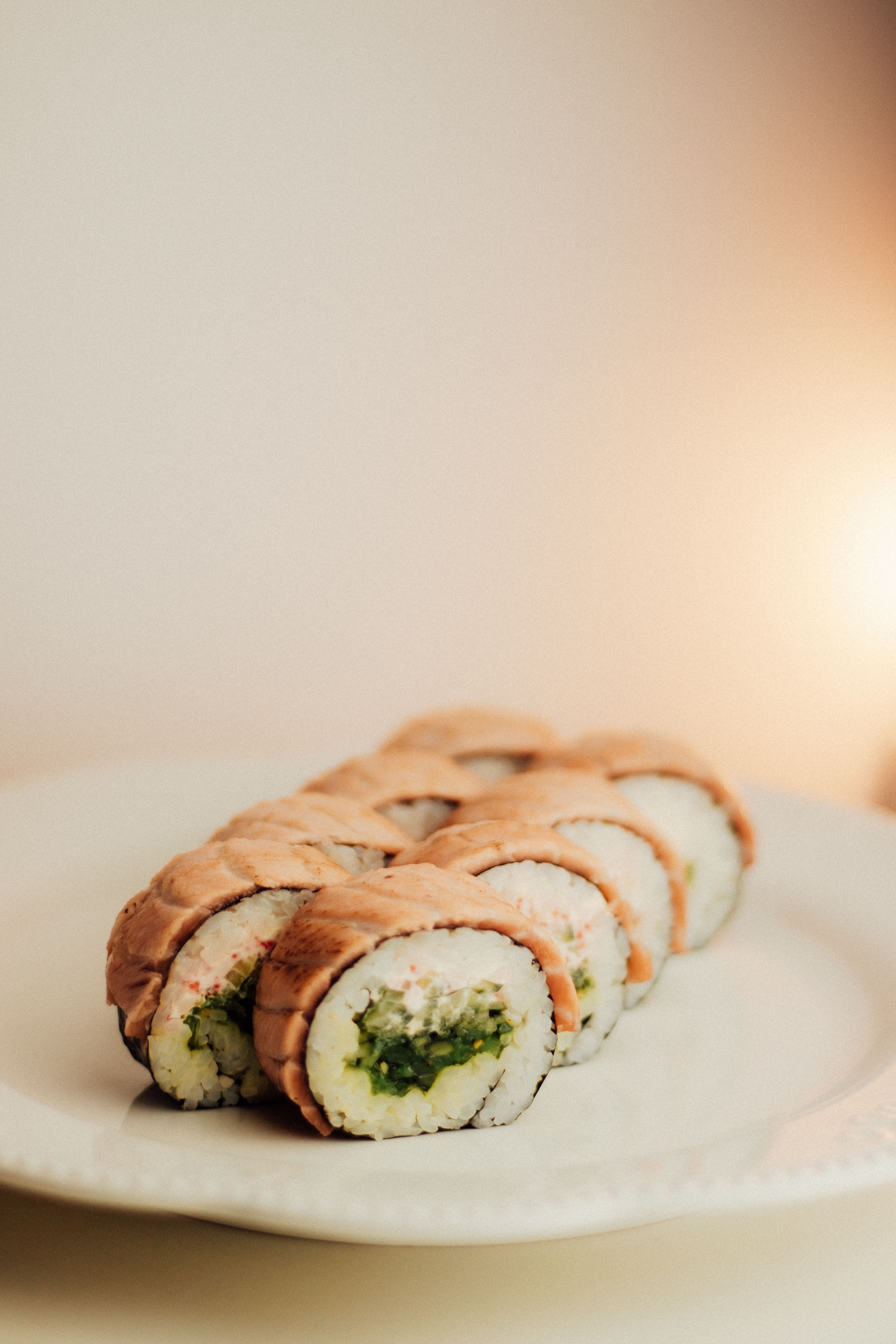 Delicious salmon sushi rolls with fresh ingredients, beautifully plated on a white dish.