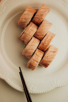 Artistic presentation of sushi rolls with chopsticks on a textured white plate.