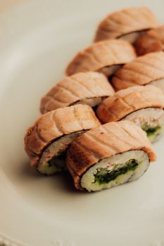 Close-up of beautifully arranged salmon sushi rolls on a white plate.