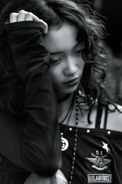 Free Black and white portrait of a young woman with curly hair, looking contemplative. Stock Photo