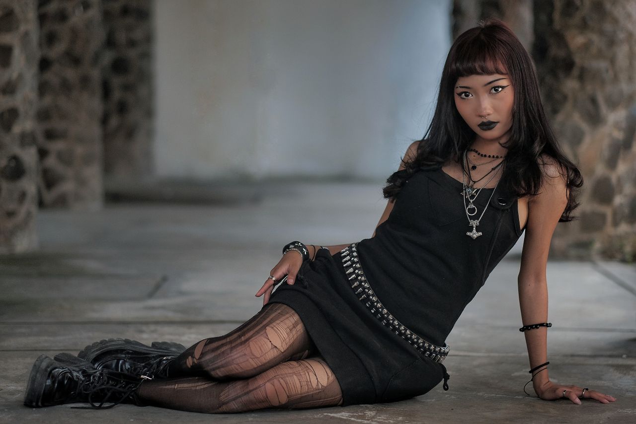 fashionable young adult in gothic attire sitting indoors