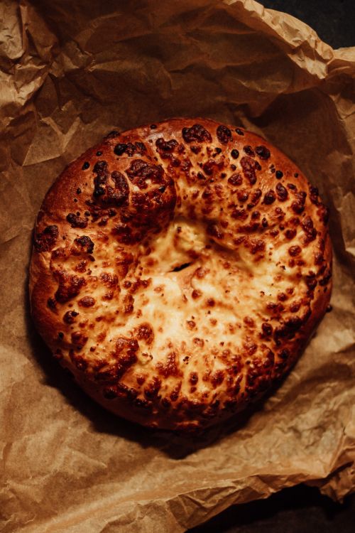 Free Freshly baked round cheese bread on rustic brown paper, evoking a warm and earthy mood. Stock Photo
