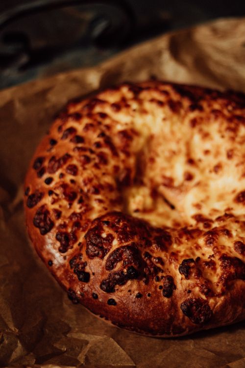 Free Close-up of a rustic homemade cheese bread on brown paper, perfect for food blogs or culinary magazines. Stock Photo