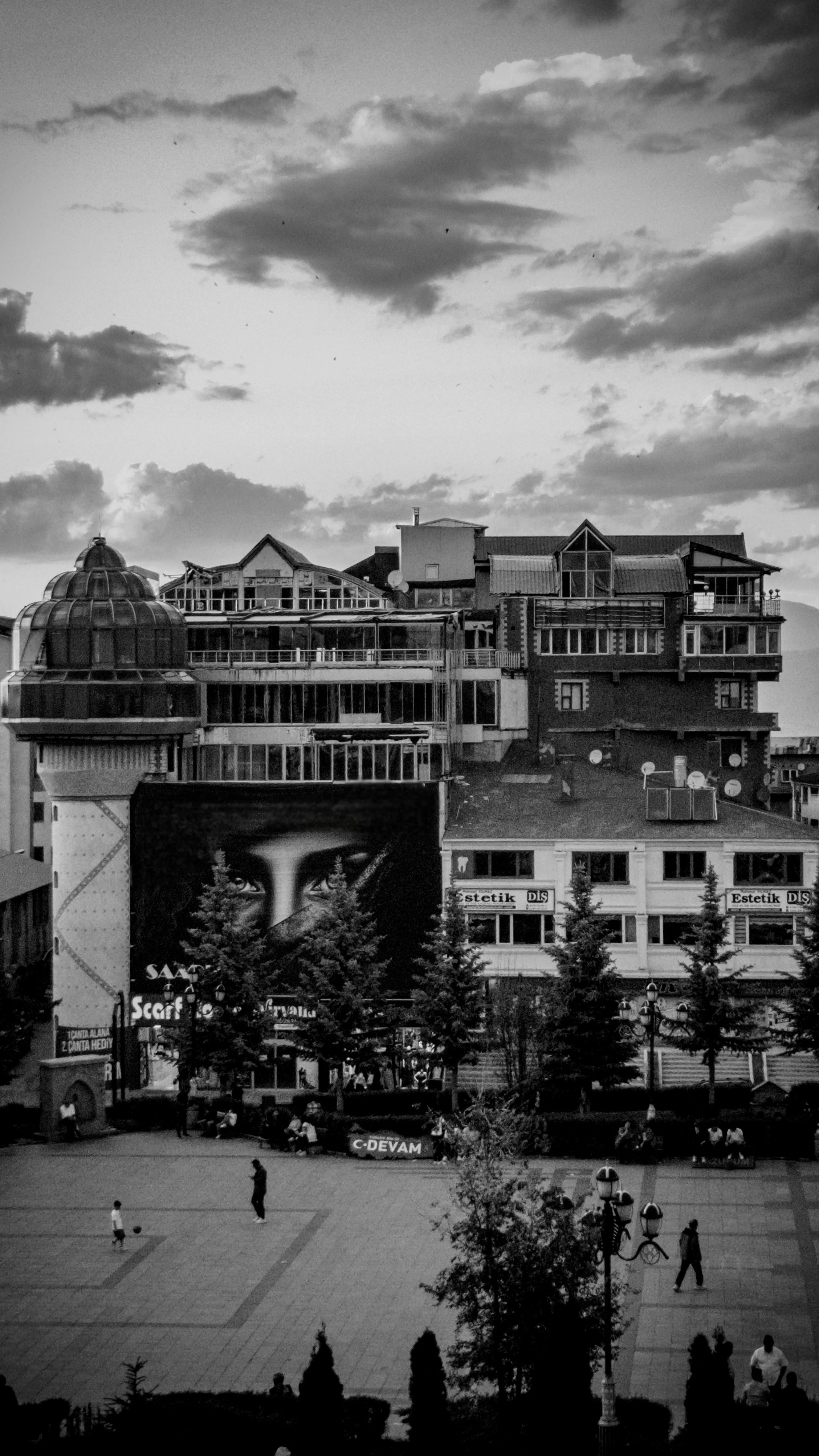 Black and white image of a lively urban square with classic architecture, creating a nostalgic cityscape.