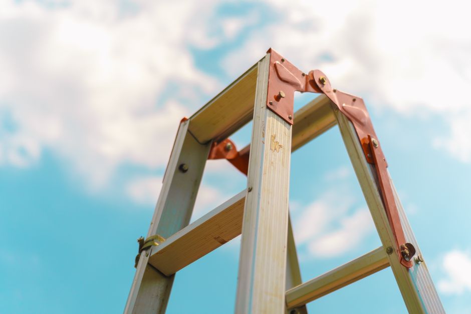 An upward view of a ladder against a bright blue sky in Makassar, Indonesia.