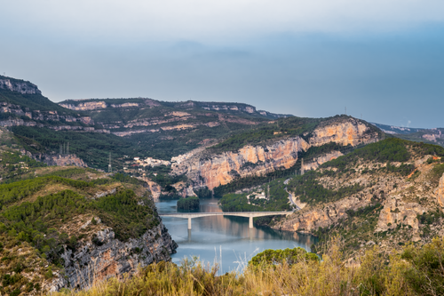 Free Panoramic view of the Cortes de Pallás valley with its reservoir and surrounding cliffs and greenery. Stock Photo