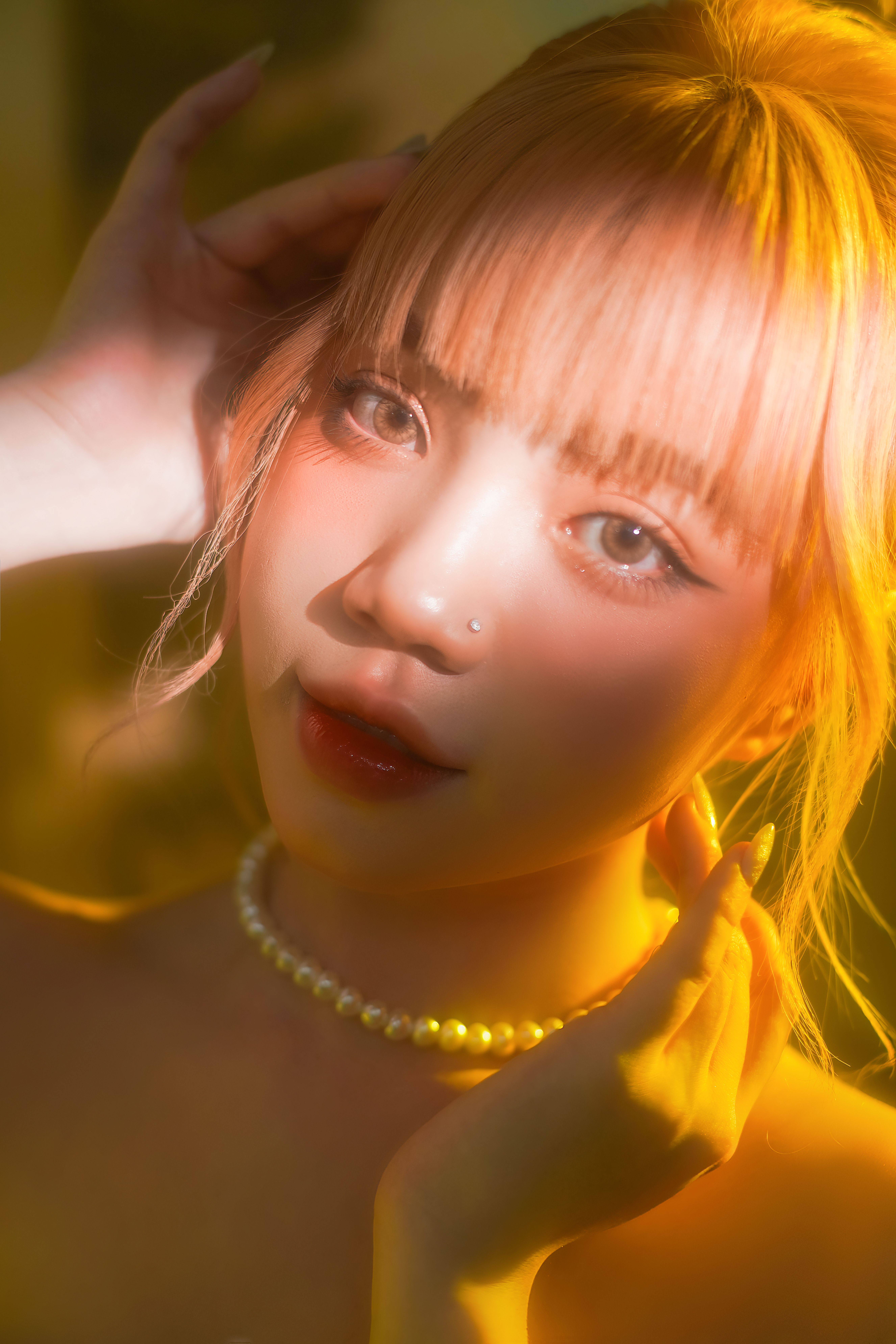 A captivating portrait of a young woman with sunlit highlights and a stylish pearl necklace.
