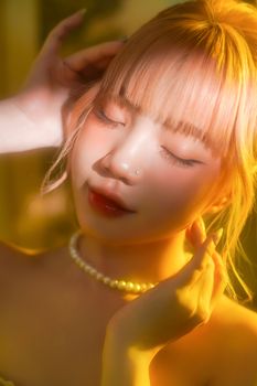 A serene close-up portrait of a young woman with closed eyes, illuminated by gentle soft light.