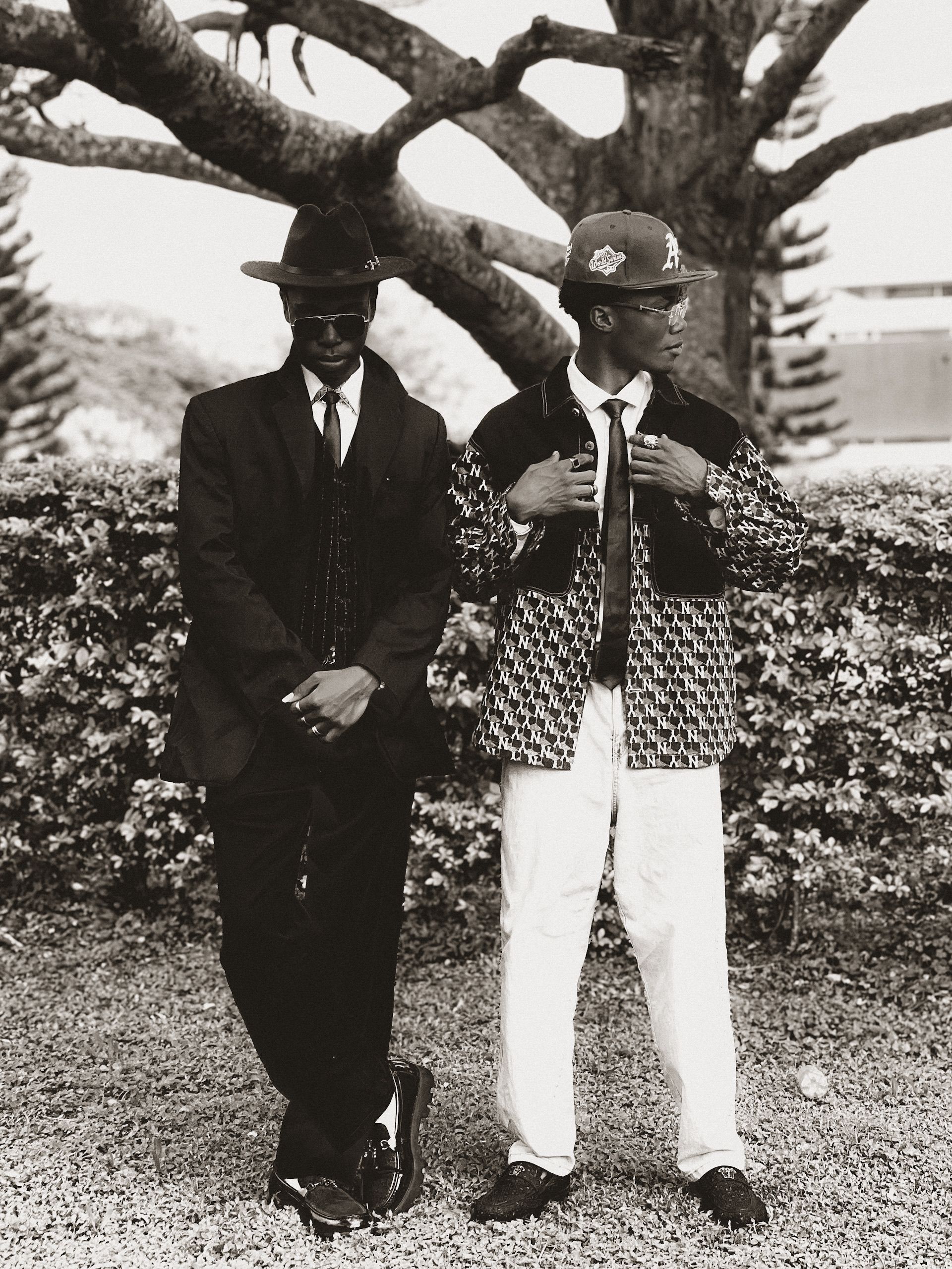 Two stylish men in vintage suits posing outdoors, exuding classic elegance.
