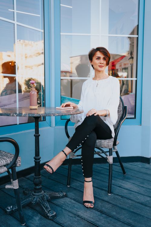 Free Fashionable woman in a casual setting sipping coffee at an outdoor café, enjoying leisure time. Stock Photo
