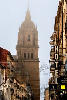 A foggy morning view of a historic tower in Salamanca, Spain's architectural landscape.