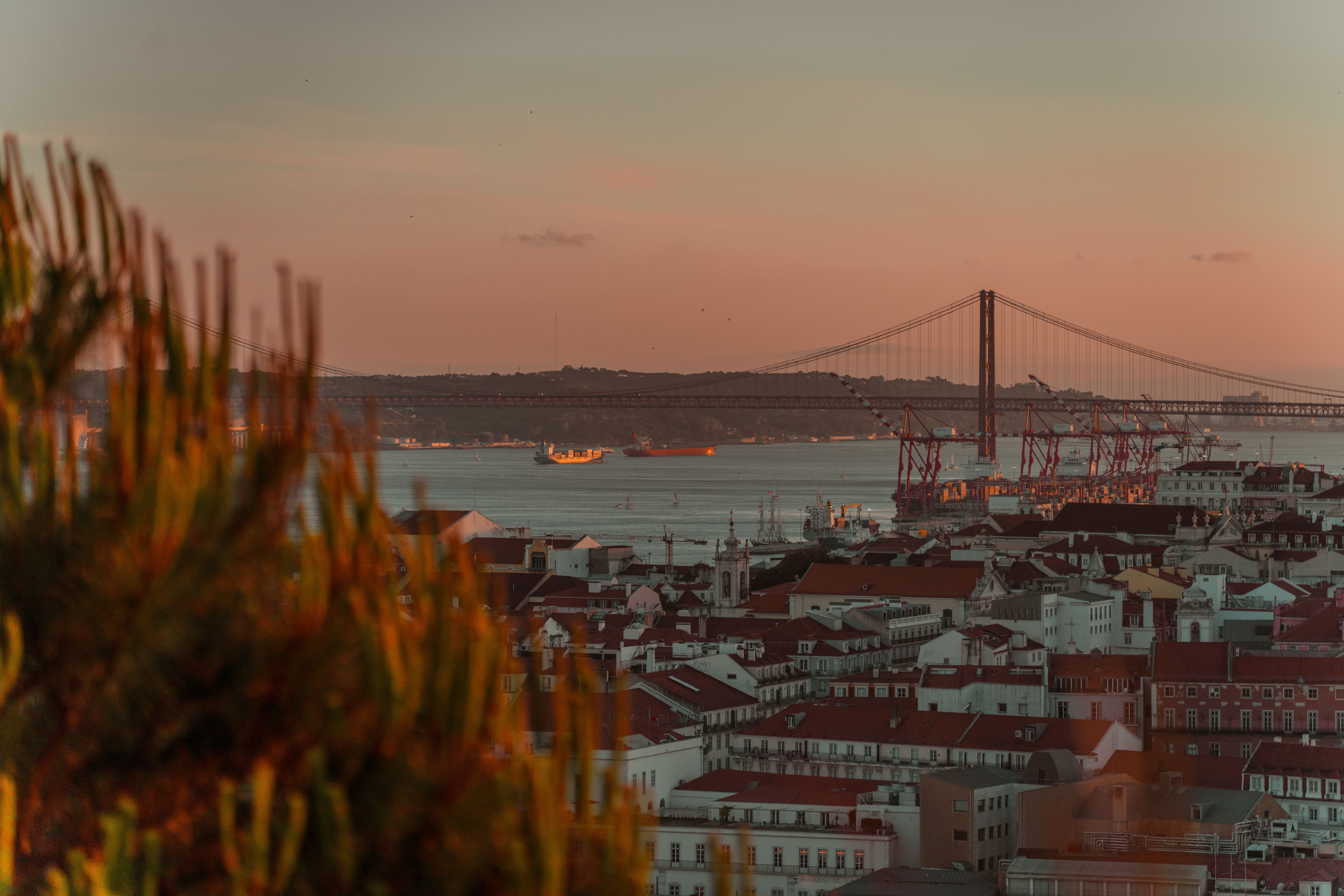 Captivating sunset view over Lisbon featuring the iconic 25th April Bridge and cityscape.