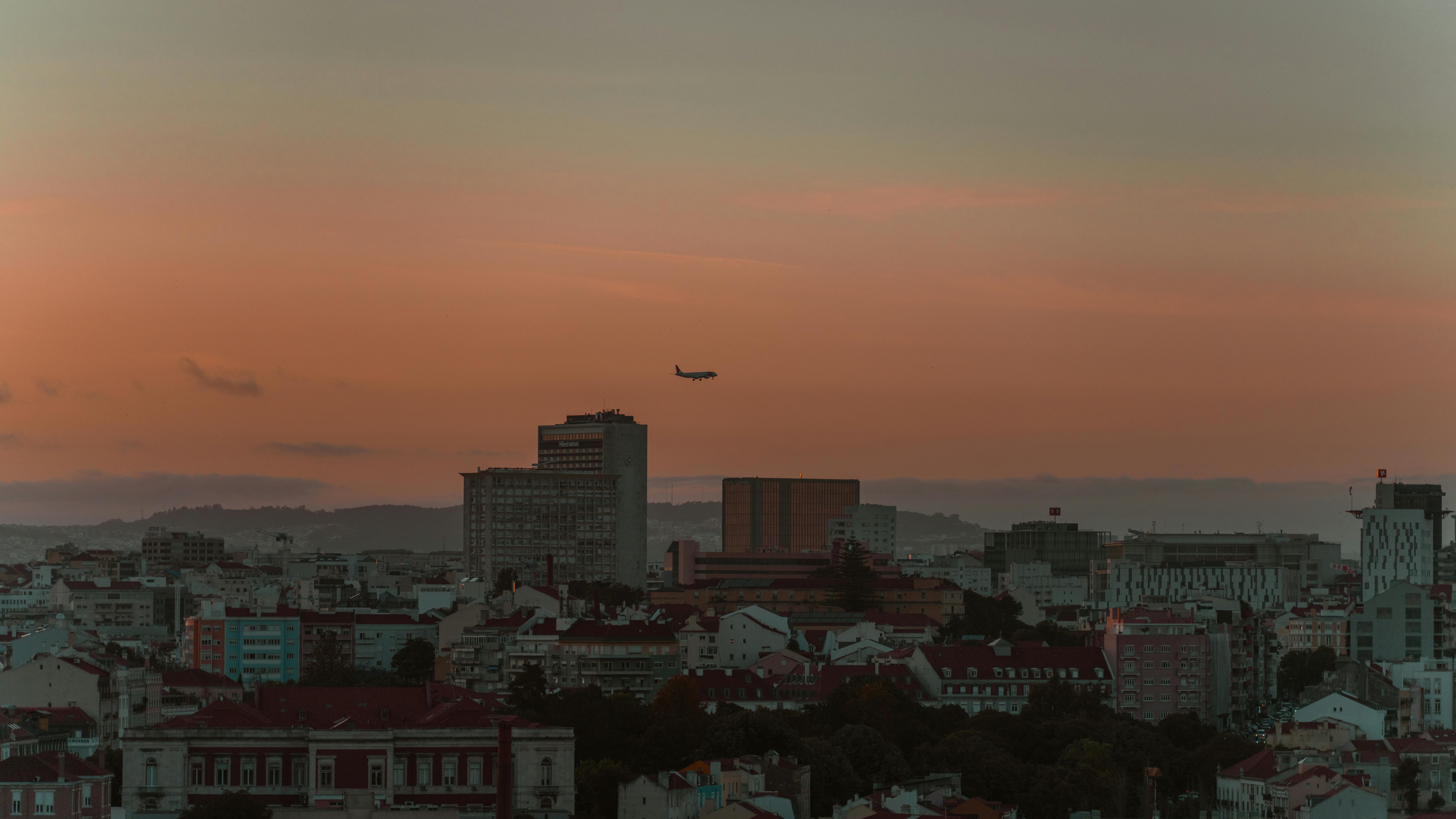 person working on laptop with a view of Lisbon's skyline at sunset