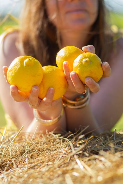 Free Colorful scene of a woman holding fresh lemons outdoors in the sunshine. Stock Photo