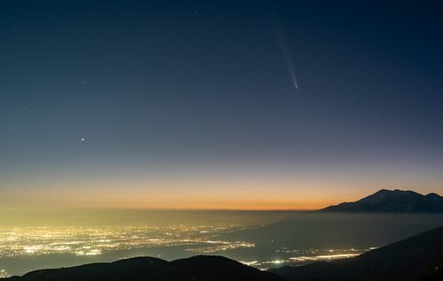 Free Beautiful night view of comet over illuminated California cityscape against a twilight sky. Stock Photo