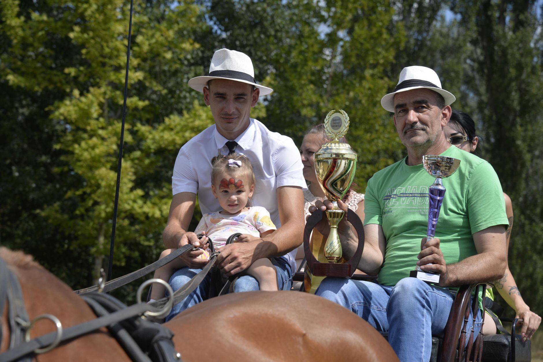 A festive moment at a horse carriage event in Tunyogmatolcs with winners holding trophies.