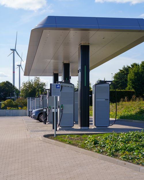 Free Electric car charging station with renewable energy wind turbines in a modern outdoor setting. Stock Photo