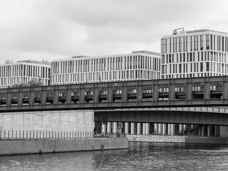Black and white photo of modern architecture over a river in Berlin, Germany.
