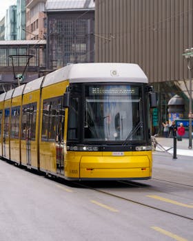 Contemporary yellow tram navigating through Berlin's cityscape, showcasing urban transportation.