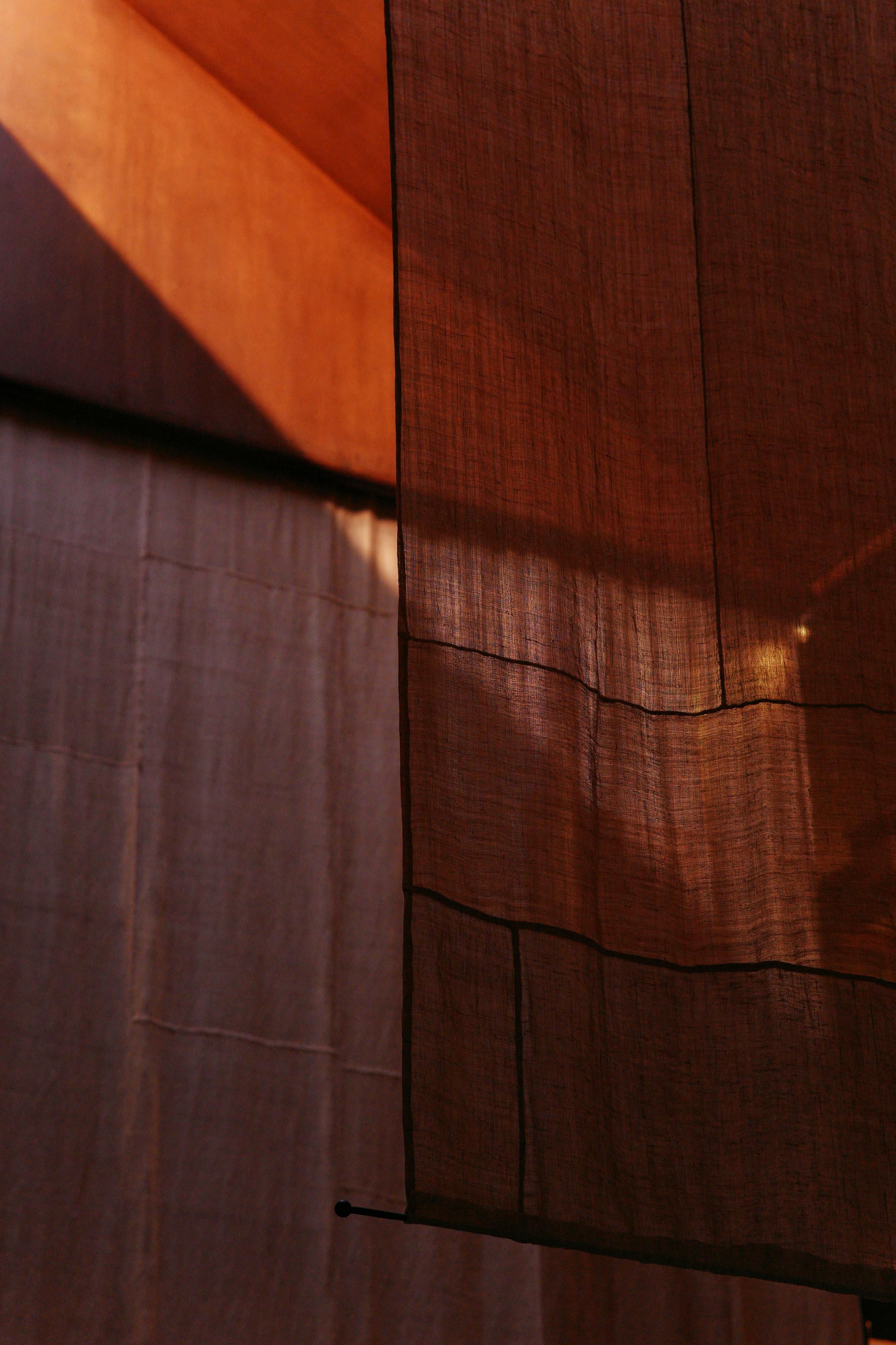 Free Soft sunlight creates a silhouette effect through brown fabric curtains, highlighting texture and warmth. Stock Photo