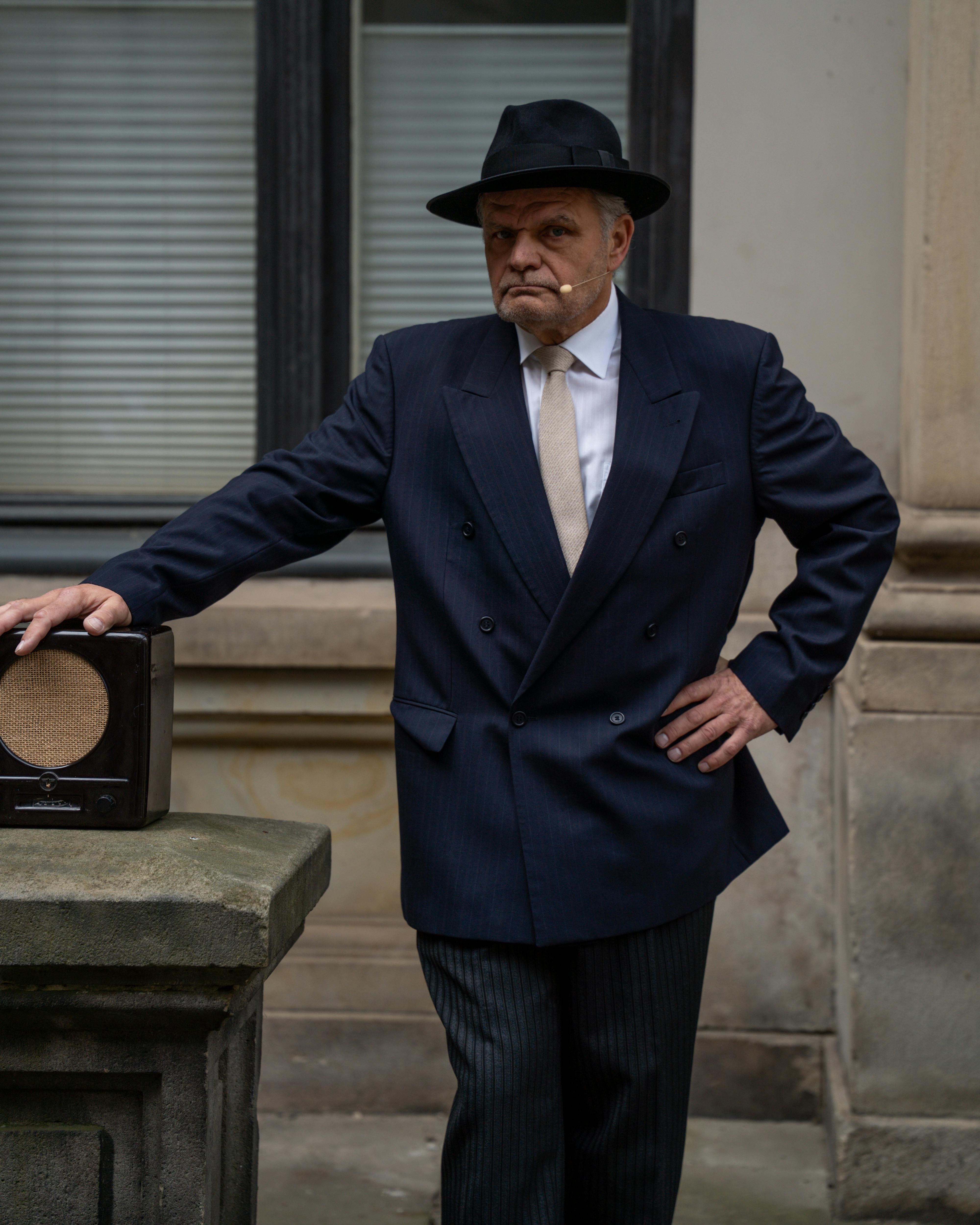 A man in vintage attire posing outdoors with a classic radio, exuding nostalgia.